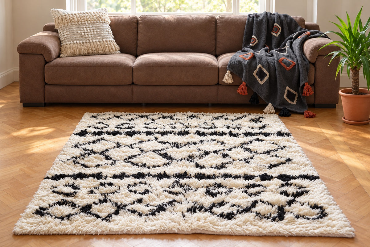Styled living room with a cream and black shaggy rug, charcoal patterned throw and cream fringed cushion